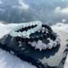 Glacial Calm Bracelet Triad in cascade style on charcoal rock with winter snow and Alpine background — Obsidian, Aquamarine and White Howlite.